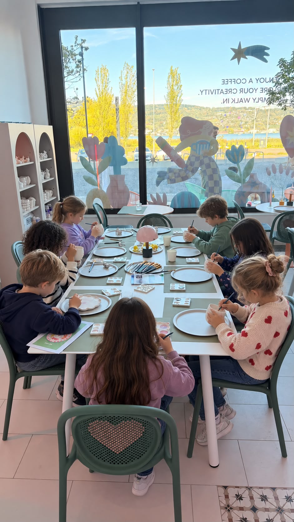 Kinder bemalen Keramik am grossen Tisch im LOVE Creative Café in Au ZH — mit Blick auf den Zürichsee