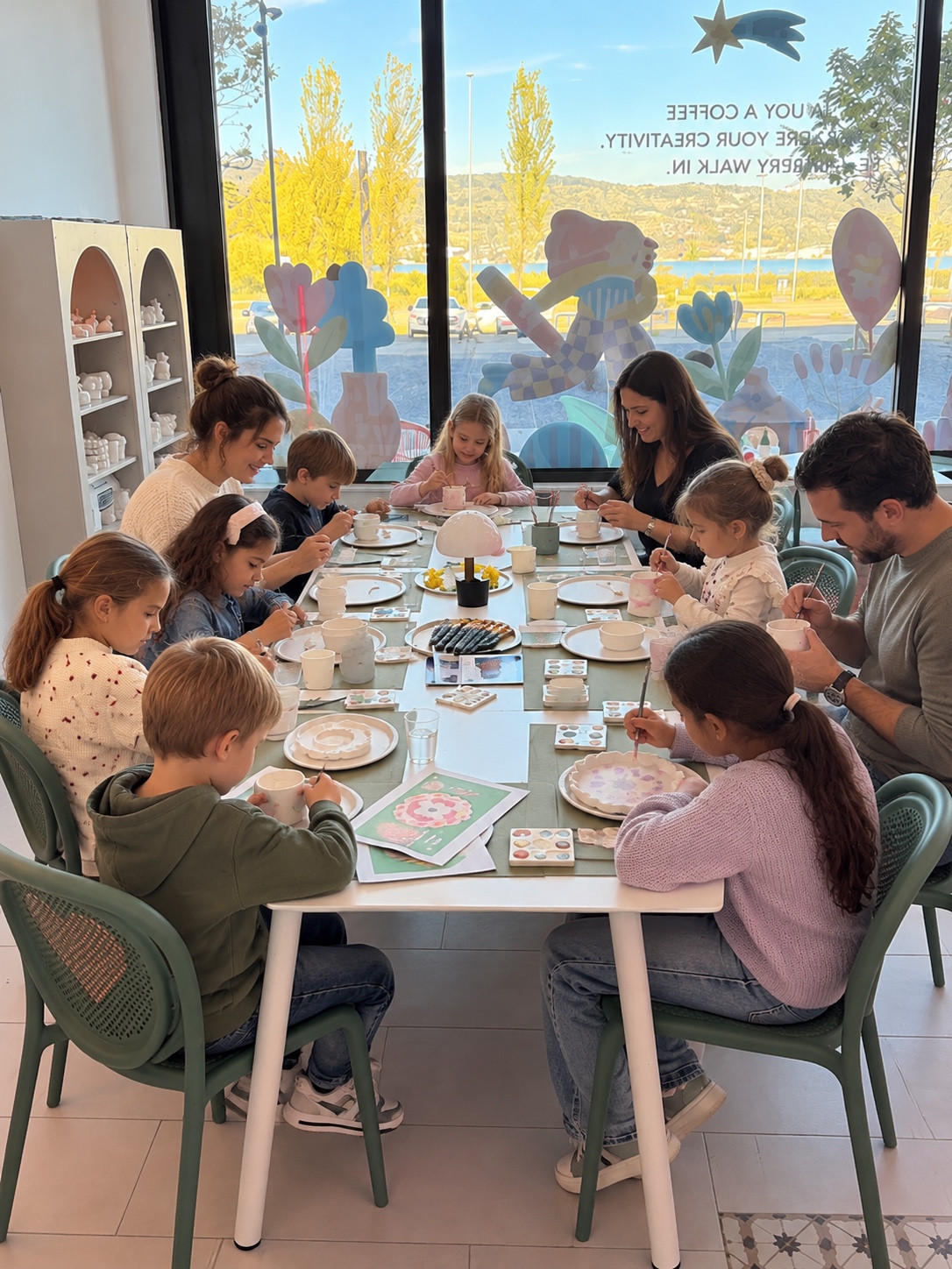 Erwachsene und Kinder bemalen gemeinsam Keramik am Tisch mit Blick auf den Zürichsee