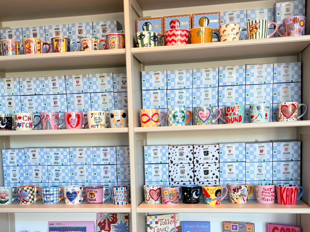 Regal mit bunten Tassen, Notizbüchern und Papeterie im LOVE Shop